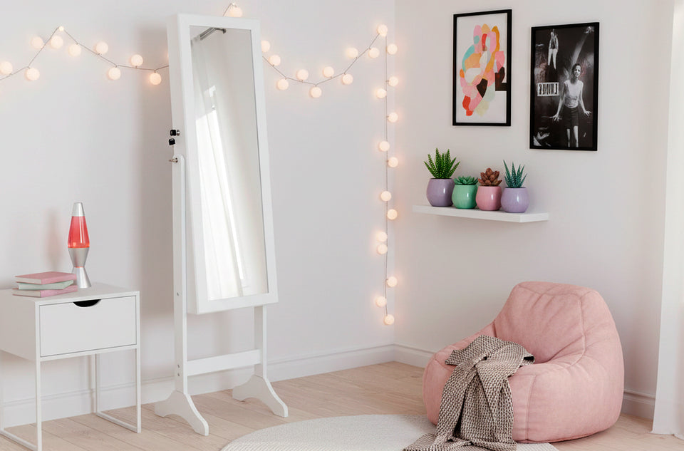 Espejo joyero blanco de pie en un dormitorio decorado con guirnalda de luces y un puf