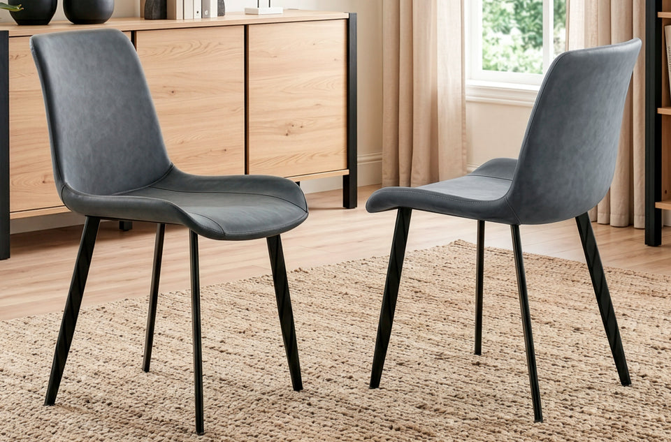 Deux chaises de salle à manger Lis Cuir gris sur un tapis, devant un buffet près de la fenêtre