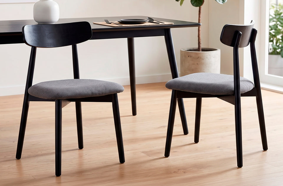 Dos sillas de comedor Shia en la variante Gris / Negro junto a una mesa de comedor